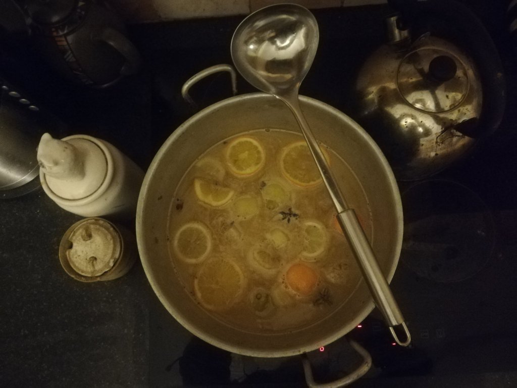 A pot of mulled cider on the hob beside jars.